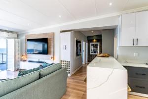 a living room with a couch and a kitchen at Beach front penthouse apartment in Ballito