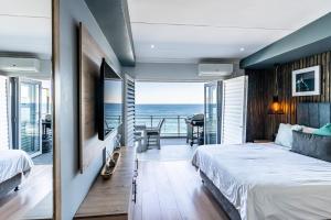 1 dormitorio con 1 cama y balcón con vistas al océano en Beach front penthouse apartment, en Ballito