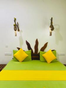 - une chambre dotée d'un lit avec des oreillers jaunes et verts dans l'établissement thambara gueust house, à Habarana