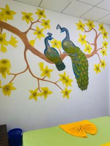 une peinture murale de deux paons sur un mur dans l'établissement thambara gueust house, à Habarana
