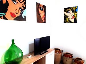レッチェにあるAppartamenti Raffaelloの壁にテレビと絵画が飾られた部屋