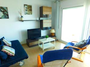 sala de estar con sofá azul y TV en GMID IMMO Apartment Mont Caliu, en Roses