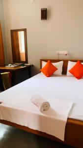 een slaapkamer met een wit bed met oranje kussens bij The Orange House Weligama in Matara