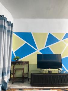 Elle comprend un salon avec une télévision et un mur bleu et jaune. dans l'établissement Marina Terrace A1-10, à Port Dickson