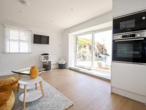 a living room with a kitchen with a large window at Beach Cottage in Helston