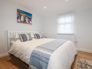 a bedroom with a white bed with a picture on the wall at Beach Cottage in Helston