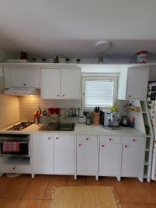 una cocina con armarios blancos y una ventana en Kenese Apartman en Balatonkenese