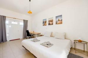 1 dormitorio con 1 cama blanca grande y escritorio en Local Guesthouse en Sagres