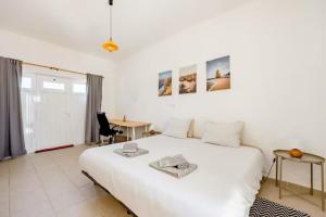 a bedroom with a large white bed and a desk at Local Guesthouse in Sagres