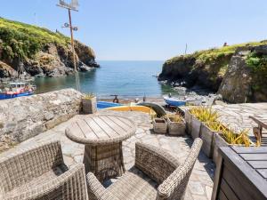a patio with a table and chairs and the ocean at Beach Cottage in Helston