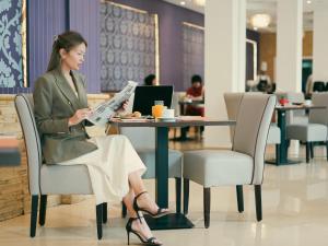 Eine Frau, die am Tisch sitzt und eine Zeitung liest. in der Unterkunft Sky Casa Airport in Nouaseur