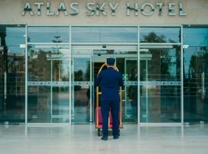 a man is standing outside of a atlas sky hotel at Sky Casa Airport in Nouaseur