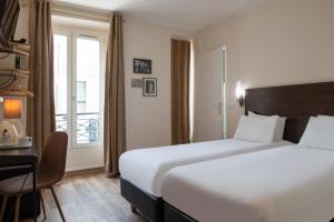 um quarto de hotel com uma cama, uma secretária e uma janela em Hôtel Istria by Magna Arbor em Paris