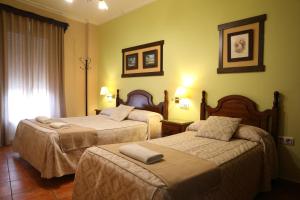 ein Hotelzimmer mit zwei Betten und einem Fenster in der Unterkunft Hostal Rocio in Sanlúcar la Mayor