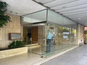 Un uomo in piedi dentro un edificio di vetro di Stylish 3 BR Family Apt in Palermo a Buenos Aires