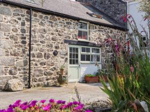 a stone cottage with a green door and flowers at The Barn at Trevothen Farm in Helston