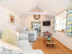 sala de estar con muebles blancos y reloj en la pared en The Barn at Trevothen Farm en Helston