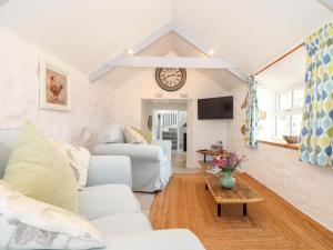 a living room with white furniture and a clock on the wall at The Barn at Trevothen Farm in Helston