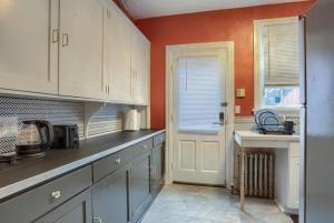 a kitchen with white cabinets and an orange wall at Charming Downtown Retreat Steps from Capitol Bldg in Harrisburg +4 photos