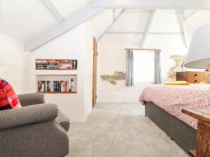 a bedroom with a bed and a chair at The Barn at Trevothen Farm in Helston