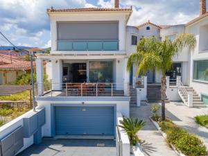 uma casa branca com uma porta de garagem azul em Maria Seaside Apartment em Sami