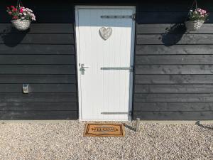 eine weiße Tür mit einem Herzschild vor einem Haus in der Unterkunft Vakantie in Duin- en Bollenstreek in Voorhout