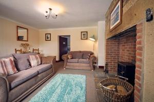 a living room with a couch and a brick fireplace at Host & Stay - Rose Cottage in Bamburgh