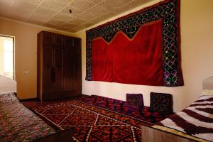 a room with a red wall with two chairs and a rug at House of Tengi Craftswomen 