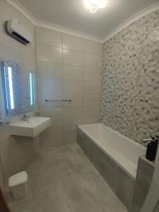 y baño con bañera y lavamanos. en Deggies Apartments - spacious, modern apartment!, en Naxxar