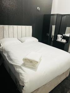 a bed with white sheets and towels on it at The Pleasant House in Manchester