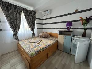a small bedroom with a bed and a refrigerator at Vila MariCris in Tuzla