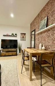 a living room with a wooden table and a brick wall at Le Marrakech Appart' T1 au centre du Mans in Le Mans