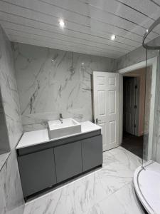 ein Badezimmer mit einem Waschbecken und einer weißen Marmorwand in der Unterkunft The Pleasant House in Manchester