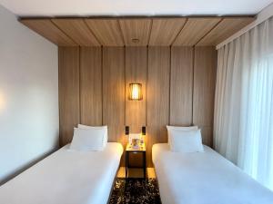 a room with two beds and a table with a window at Radisson Pinheiros in São Paulo