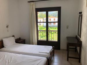 a bedroom with two beds and a large window at Hotel Apartment Agios Konstantinos in Ágios Konstantínos
