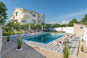 a villa with a swimming pool and lounge chairs at Apartman David s bazenom i jakuzijem in Podušje