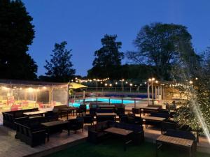 a patio with tables and chairs and a pool at night at Le Petit Moulin du Rouvre in Saint-Pierre-de-Plesguen