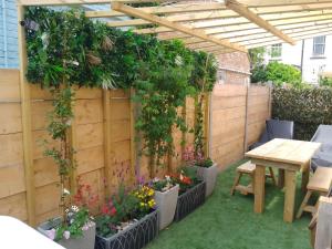 a garden with a pergola and a table with plants at 1 The Old Schoolhouse for 5+cot; hot tub, parking, pets in Whitstable