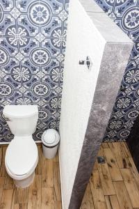 a bathroom with a toilet and a wall with tiles at Pelicano Inn Playa del Carmen - Beachfront Hotel in Playa del Carmen