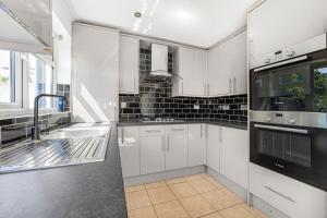 a kitchen with white cabinets and a sink at Rose Terrace in London