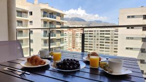 uma mesa com alimentos e bebidas ao pequeno-almoço numa varanda em CALA ALTA sunrise apartments em Benidorm