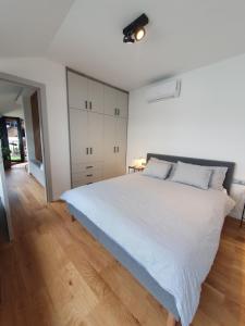 a white bedroom with a large bed and wooden floors at Modern top floor loft with balcony in Budapest