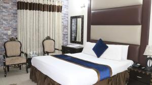 a bedroom with a large bed and two chairs at HOTEL TOURIST INN in Lahore