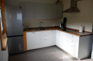 a kitchen with white cabinets and a stainless steel refrigerator at Maślany Domek in Sokolec