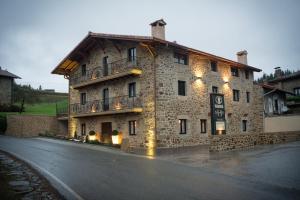 un gran edificio de piedra con luces laterales en Osabarena Hotela, en Murueta-Orozko