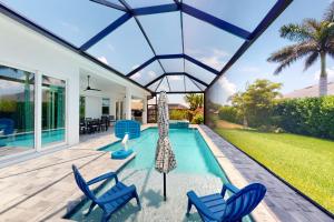 a house with a swimming pool and two blue chairs at Island Escape in Marco Island