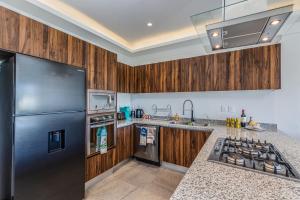 a kitchen with wooden cabinets and a stainless steel refrigerator at Believe 3BR Condo Flamingos by Casago in Bucerías