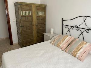 Schlafzimmer mit einem weißen Bett und einem Holzschrank in der Unterkunft ESPACIO Y LUZ en Isla Cristina Capacidad hasta 8 HUESPEDES in Isla Cristina