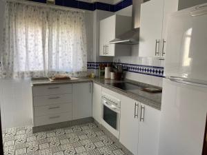 eine weiße Küche mit weißen Schränken und einem Fenster in der Unterkunft ESPACIO Y LUZ en Isla Cristina Capacidad hasta 8 HUESPEDES in Isla Cristina