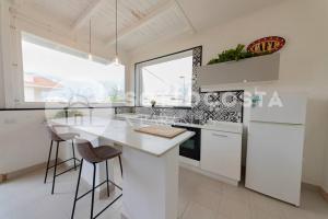 una cocina blanca con encimera blanca y taburetes en Surf Flat, en San Foca 30 fotos más